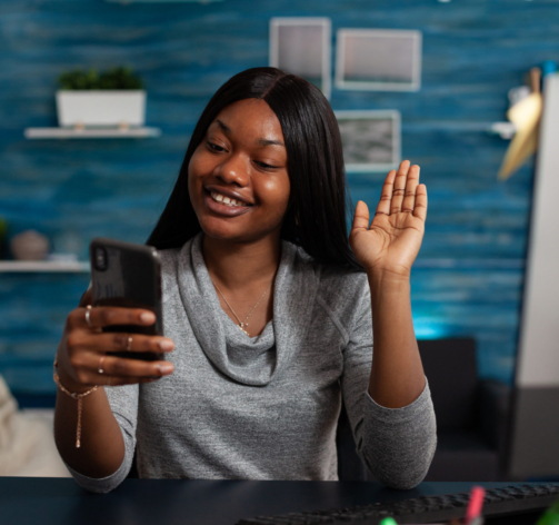 Person using video call on phone to talk to colleagues from home. Entrepreneur doing business meeting on smartphone with online video conference, waving at mobile phone camera. Remote work